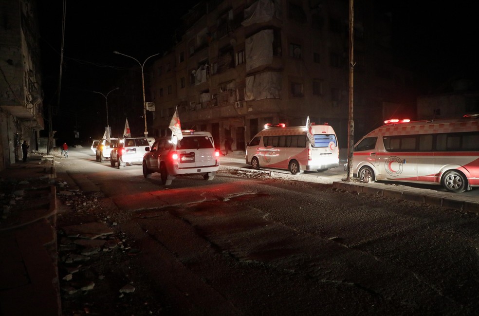 As ambulâncias do Crescente Vermelho sírio fazem fila para transportar pacientes durante uma operação de evacuação coordenada com o Comitê Internacional da Cruz Vermelha em Douma, na região Ghouta do leste rebelde, na Síria, nesta quarta (27) (Foto: Abdullah Hammam/AFP)
