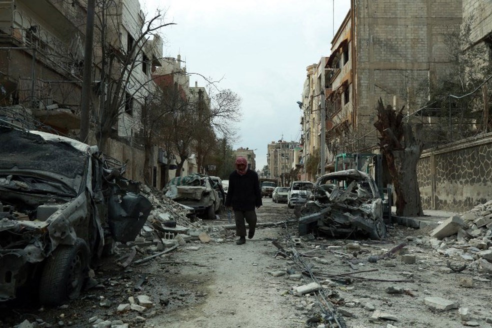 Sírio caminha entre prédios destruídos em Duma, cidade de Guta Oriental, neste domingo (25), oito dias após a intensificação do conflito na região  (Foto: Hamza Al-Ajweh / AFP )