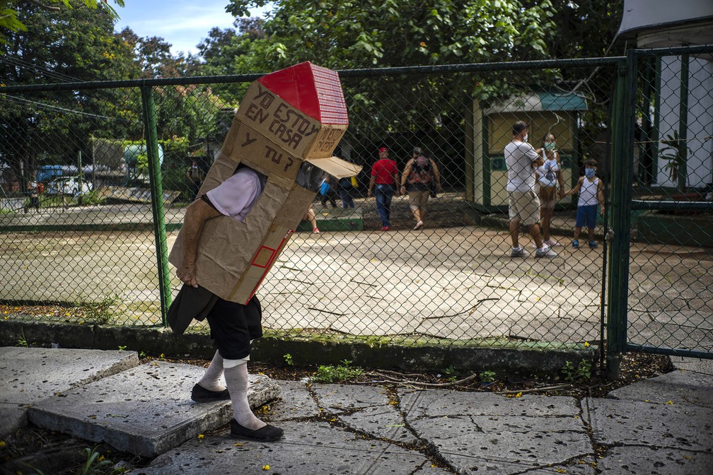 8 de julho - Feridia Rojas, uma enfermeira aposentada, usa caixa de papelão como medida protetora contra a propagação do coronavírus (Covid-19), em Havana, Cuba. A aposentada de 82 anos de idade sai às ruas de Havana para fazer compras  usando a caixa de papelão com uma mensagem manuscrita em espanhol: 'Estou em casa e você?' — Foto: Ramon Espinosa/AP