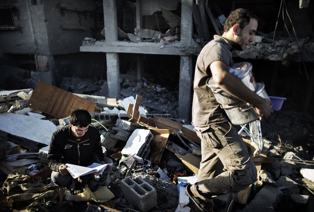 Palestinos tentam recuperar pertences em casa atingida por ataque aéreo na Faixa de Gaza neste domingo (Foto: Marco Longari/AFP)
