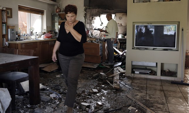 Mulher israelense numa casa danificada por foguete lançado de Gaza, em 2012