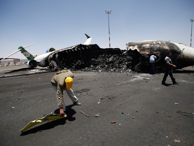 Funcionários de Felix Airways, uma companhia aérea doméstica, inspecionam um avião destruído por ataques aéreos liderados por sauditas no aeroporto International de Saná, no Iêmen (Foto: Hani Mohammed/AP)