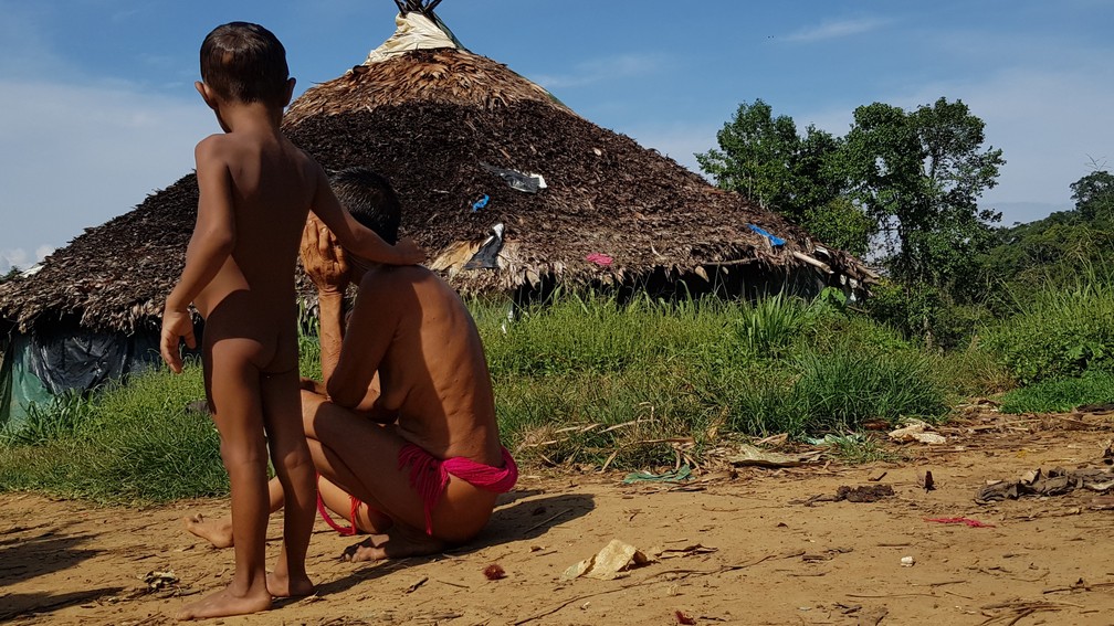 Mulher Yanomami com sintoma de malária tenta se aquecer sob o sol para aliviar os calafrios causados pela doença — Foto: Valéria Oliveira/g1