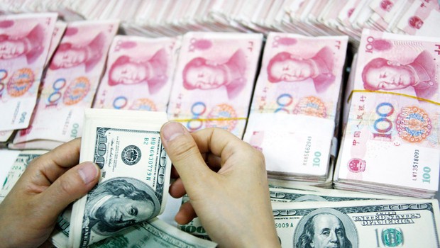 Funcionário conta notas de yuan e dólares em uma filial do Banco Comercial e Industrial da China em Huabei, província da China ; câmbio na China ; (Foto: ChinaFotoPress/Getty Images)