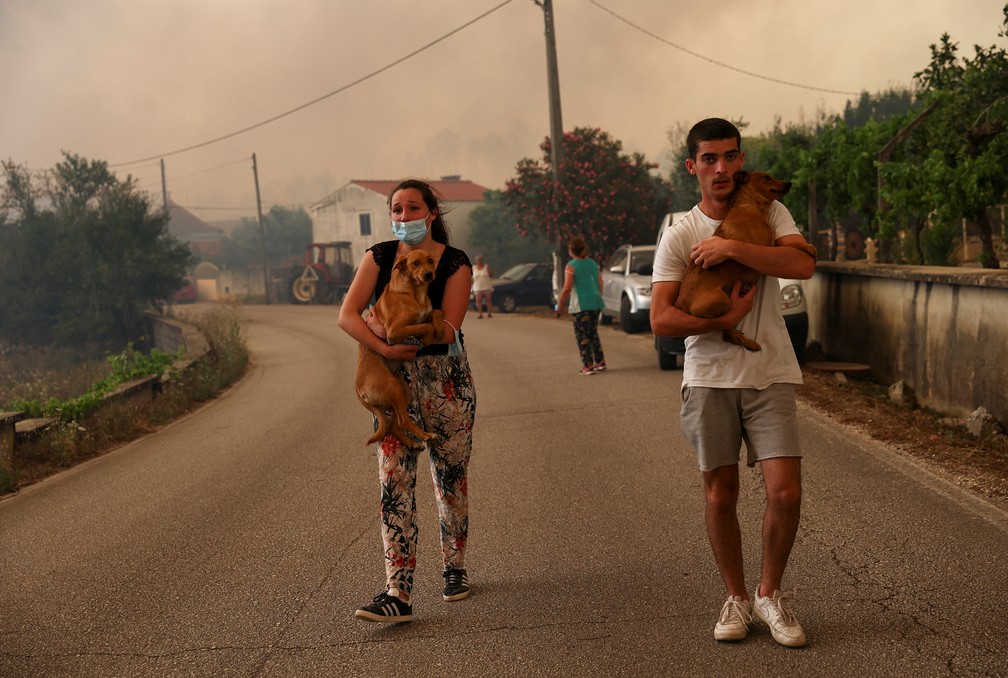 Pessoas carregam cachorros enquanto são retiradas de suas casas devido a um incêndio florestal em Leiria, Portugal.  — Foto: Rodrigo Antunes/Reuters