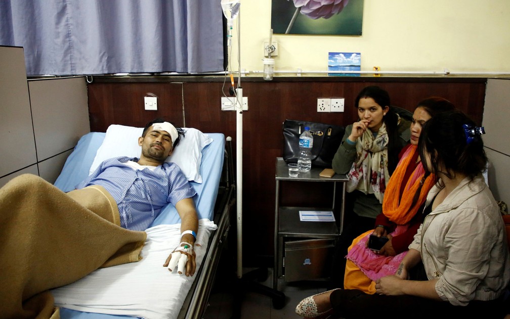 Basanta Bohara, de 27 anos, sovrevivente do acidente de avião no aeroporto de Katmandu, no Nepal, é visto em hospital ao lado de familiares na segunda-feira (12) (Foto: Reuters/Navesh Chitrakar)