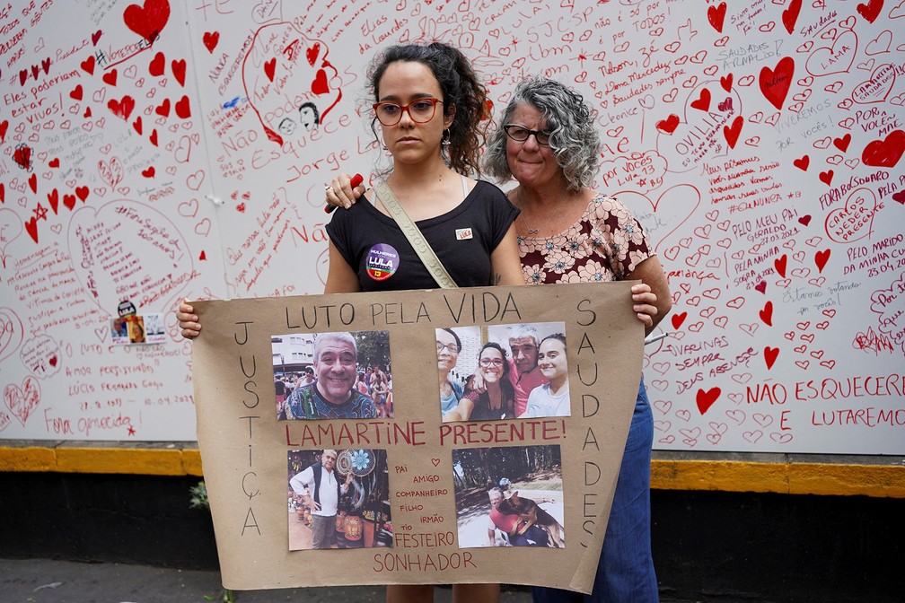 Familiares de uma vítima da Covid mostram um cartaz diante do memorial erguido na Avenida Paulista, em São Paulo, para lembrar as vítimas de Covid — Foto: Mariana Greif/Reuters