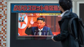 Homem passa por uma tela de TV que exibe notícia sobre o último lançamento de mísseis norte-coreanos, com imagens do líder do Norte, Kim Jong-Un, em Tóquio. — Foto: Richard A. Brooks / AFP