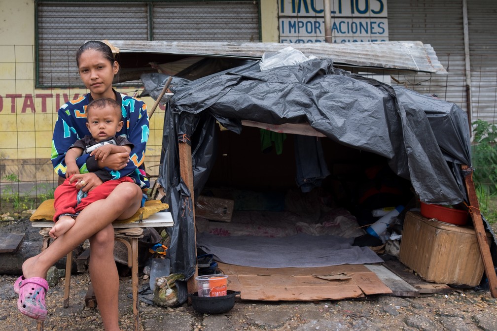 Angélia Aguilera, 18, e o filho de 2 anos ao lado da barraca em que estão vivendo há cerca de 1 mês; 'Na rua é muito frio' (Foto: Inaê Brandão/G1 RR)