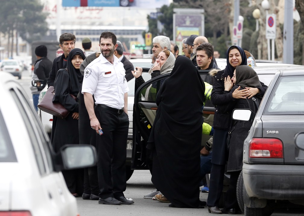 Familiares de vítimas de avião que caiu no Irã aguardam notícias em frente de mesquita próxima ao aeroporto do Teerã  (Foto: ATTA KENARE / AFP)