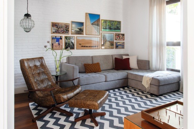 Na sala de TV projetada pela arquiteta Luciana Galves, os quadros estão alinhados na altura do sofá. As fotografias de viagem tiradas pelos moradores têm a mesma paleta de cores (Foto: Cacá Bratke / Divulgação)