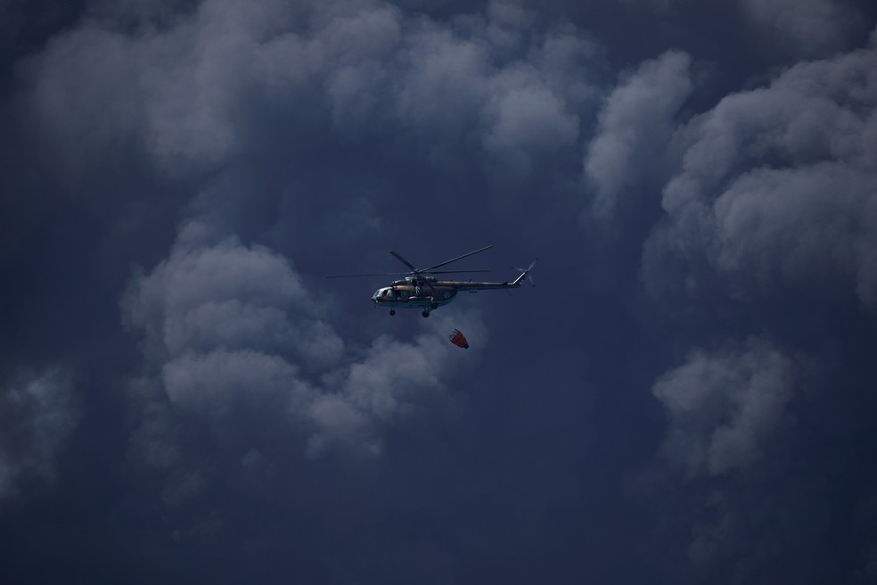 Helicóptero se prepara para jogar água em foco de incêndio em tanque de petróleo em Cuba, em 7 de agosto de 2022 — Foto: Alexandre Meneghini/Reuters