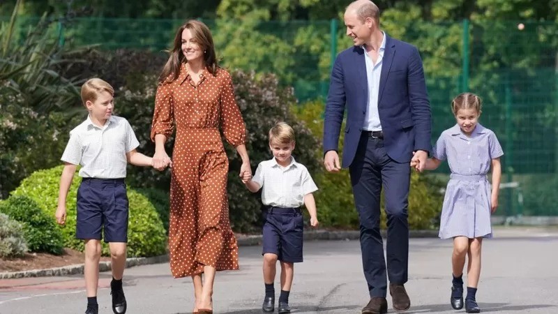 Os príncipes George e Louis e a princesa Charlotte caminham de mãos dadas com os pais, o duque e a duquesa da Cornualha e de Cambridge, no primeiro dia de aula (Foto: PA MEDIA via BBC)