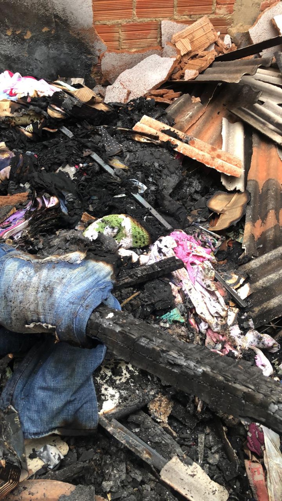 Roupa de bebê rosa entre os destroços de um incêndio em residência de Porto Velho — Foto: Thais Gomes/Rede Amazônica