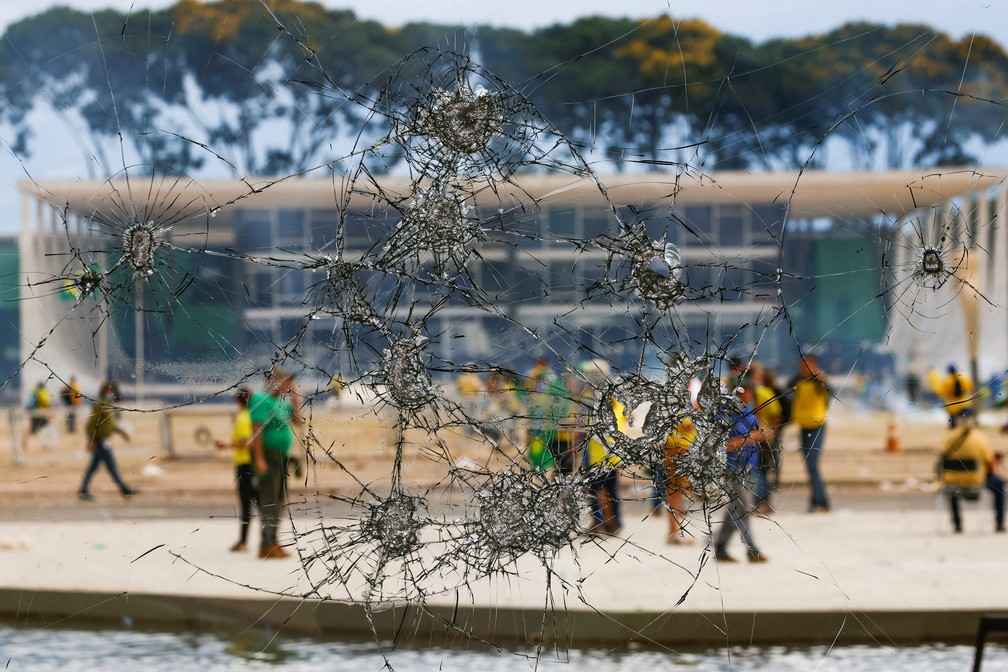 Criminosos são vistos através de janela vandalizada do Palácio do Planalto, em Brasília — Foto: Adriano Machado/Reuters