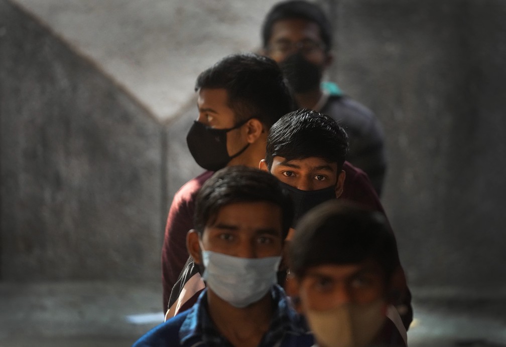 Crianças fazem fila para receber a vacina para Covid-19 em uma escola do governo em Nova Delhi, na Índia. As autoridades de saúde do pais começaram a vacinar adolescentes na faixa etária de 15 a 18 anos nesta segunda (3)   — Foto: Manish Swarup/AP