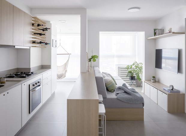 O apartamento de 55 m² tem cozinha e sala integrados por um mesmo móvel que faz as vezes de bancada e sofá (Foto: Divulgação)