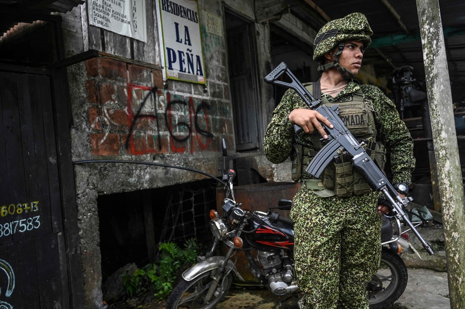 Soldado colombiano monta guarda ao lado de pichações de guerrilheiros no departamento de Vale do Cauca