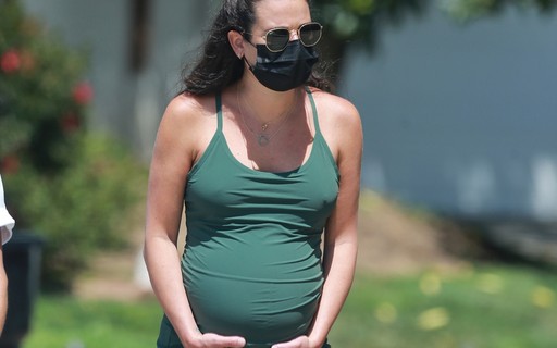Lea Michele caminha segurando o barrigão na reta final da gravidez