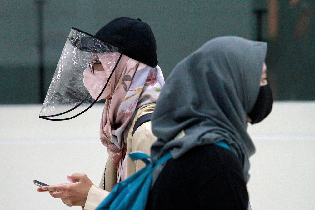 Mulheres são fotografadas usando máscara protetora e protetor facial na Indonésia — Foto: Ajeng Dinar Ulfiana/Reuters