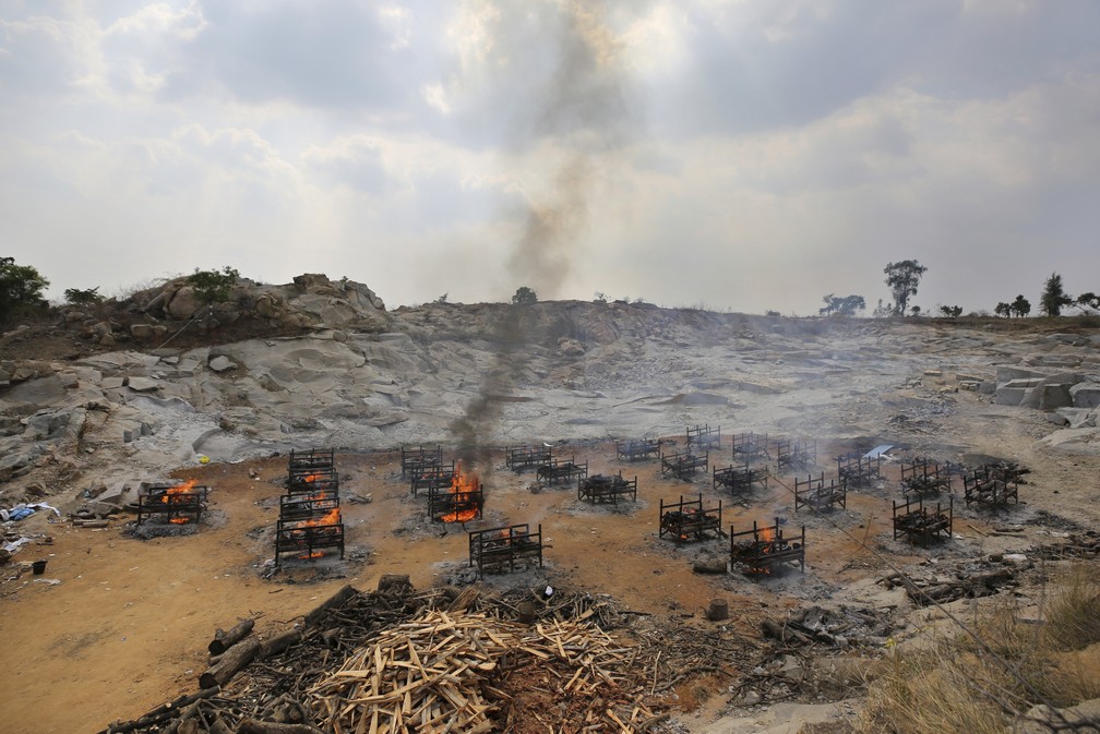 Piras funerárias de 25 vítimas da Covid-19 queimam em crematório a céu aberto criado em uma pedreira de granito nos arredores de Bengaluru, na Índia, em 5 de maio de 2021 — Foto: Aijaz Rahi/AP