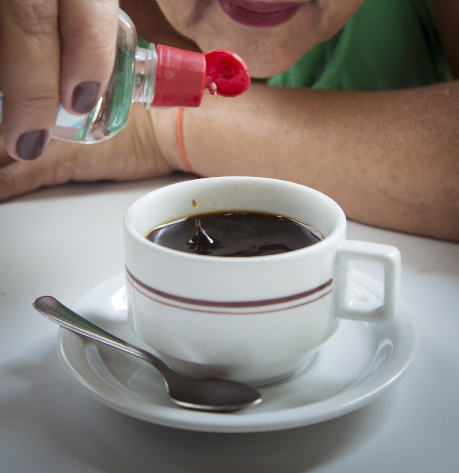 Mulher coloca adoçante no café.