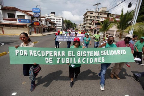 Manifestantes participam de passeata na Cidade do Panamá, Panamá. Na foto, carregam um cartaz pedido a volta do sistema solidário da previdência