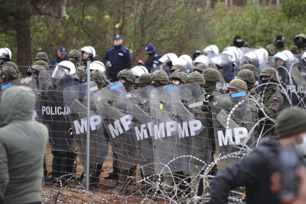 Policiais e militares poloneses fazem barreira na fronteira da Polônia com Belarus nesta segunda (8) para evitar entrada de migrantes do Oriente Médio — Foto: Leonid Shcheglov/BelTA via AP