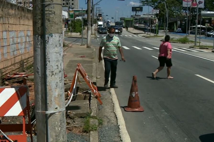 Cratera aberta em calçada faz pedestres circularem pela Avenida das Amoreiras, em Campinas