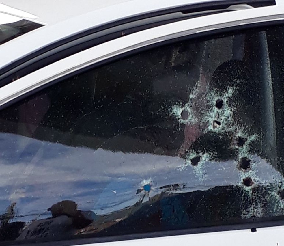 Marcas dos tiros ficaram no vidro da porta do carro onde estavam as vÃ­timas (Foto: ReproduÃ§Ã£o/WhatsApp)