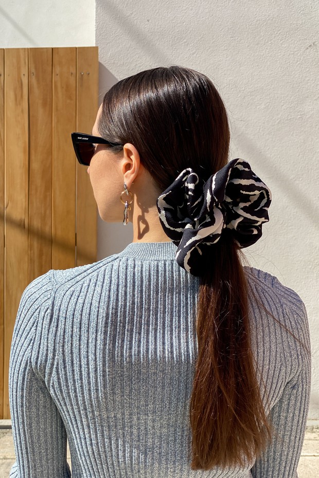 PARIS, FRANCE - MARCH 05: Julia Comil wears Saint Laurent YSL sunglasses, earrings, a wool gray rib top by Theory, a maxi black and white zebra print scrunchie by Autumn Adeigbo, during an online remote fashion photo session via Apple iphone / Facetime an (Foto: Getty Images)