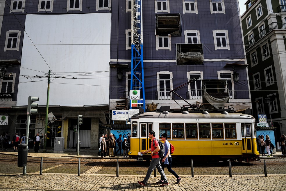 Turistas passam em frente a um prÃ©dio em reforma em Lisboa, Portugal â Foto: Patricia de Melo Moreira/AFP