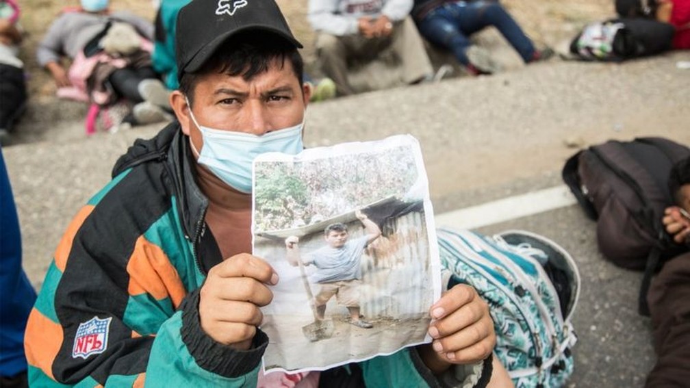 Wilmer, um hondurenho da caravana de migrantes que atravessa a Guatemala, mostra uma foto de sua casa destruída pela tempestade Eta, motivo pelo qual decidiu ir para os EUA — Foto: EPA/BBC