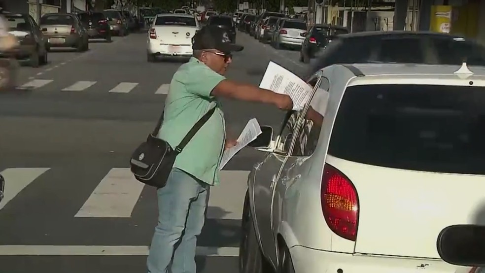 Josias Freire entrega panfleto com informações do currículo para pedir emprego, nos semáforos de João Pessoa (Foto: TV Cabo Branco/Reprodução)