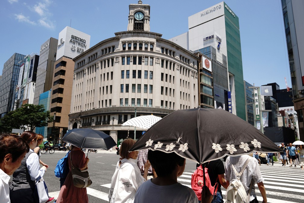 Pessoas caminham sob sol intenso na sexta-feira (20) em Tóquio, no Japão  (Foto: Eugene Hoshiko/AP)