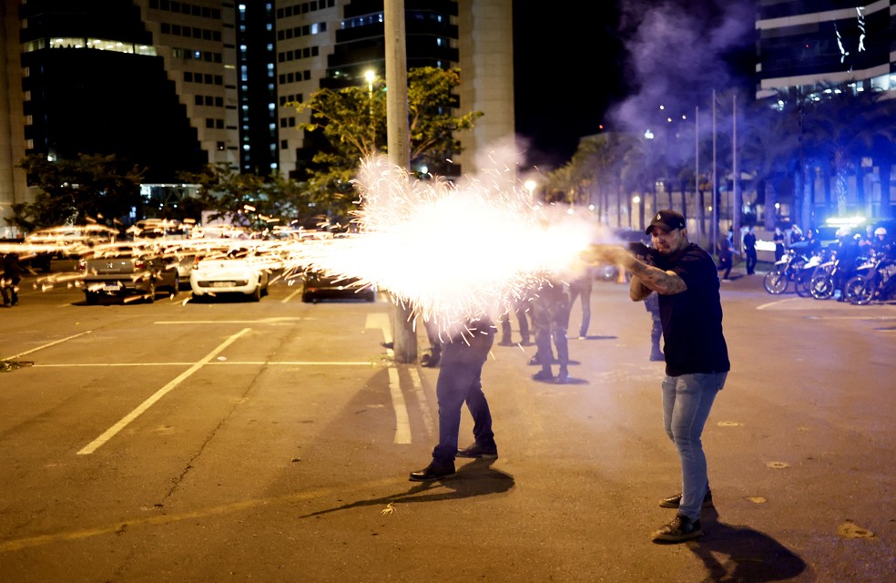Policial reage contra bolsonaristas radicais que tentaram invadir prédio da PF em Brasília, na noite desta segunda-feira (12). — Foto: Ueslei Marcelino/Reuters