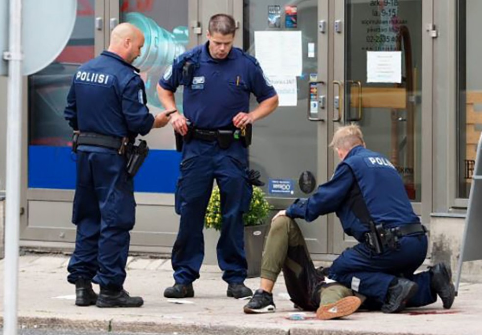 Uma pessoa é atendida por policial no chão em Turku (Foto: KIRSI KANERVA / AFP)