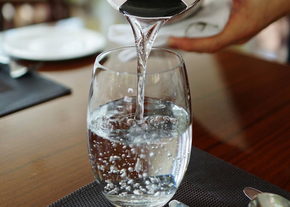 Imagem ilustrativa de uma pessoa colocando água num copo