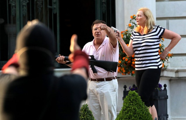 Armed homeowners Mark T. and Patricia N. McCloskey stand in front their house along Portland Place as they confront protesters marching to St. Louis Mayor Lyda Krewson&apos;s house Sunday, June 28, 2020, in the Central West End of St. Louis. The protester (Foto: TNS via Getty Images)