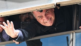 Ex-presidente Bolsonaro cumprimenta apoiadores de uma janela na sede do Partido Liberal em Brasília. Ele retorna depois de 89 dias nos EUA — Foto: Evaristo Sá/AFP