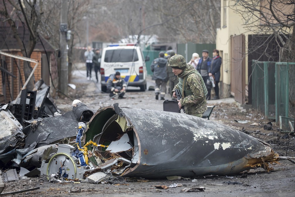 25 de fevereiro - Um soldado do exército ucraniano inspeciona fragmentos de uma aeronave derrubada em Kiev, Ucrânia — Foto: Vadim Zamirovsky/AP