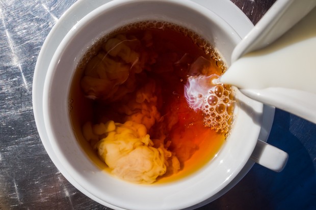 Milk is poured into a cup of tea on a metallic table. (Foto: Getty Images/iStockphoto)