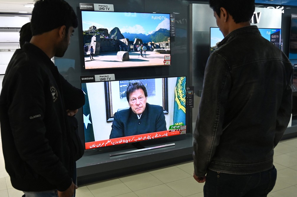 Paquistaneses assistem ao discurso do primeiro-ministro paquistanês, Imran Khan, na televisão em Islamabad, nesta terça-feira (19)  — Foto: Aamir Qureshi / AFP
