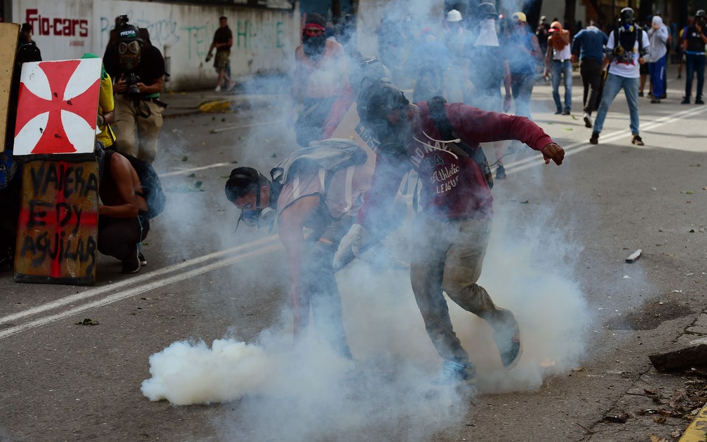 Manifestantes se preparam para atirar de volta bombas de gás em policiais durante protesto contra o governo em Caracas, na Venezuela, na quinta-feira (20) (Foto: Ronaldo Schemidt/AFP)