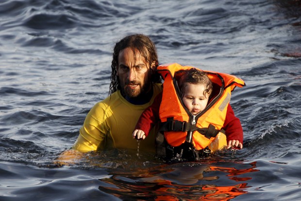 Voluntário carrega bebê que estava em barco com 150 refugiados que virou nesta sexta-feira (30) (Foto: Giorgos Moutafis/Reuters)