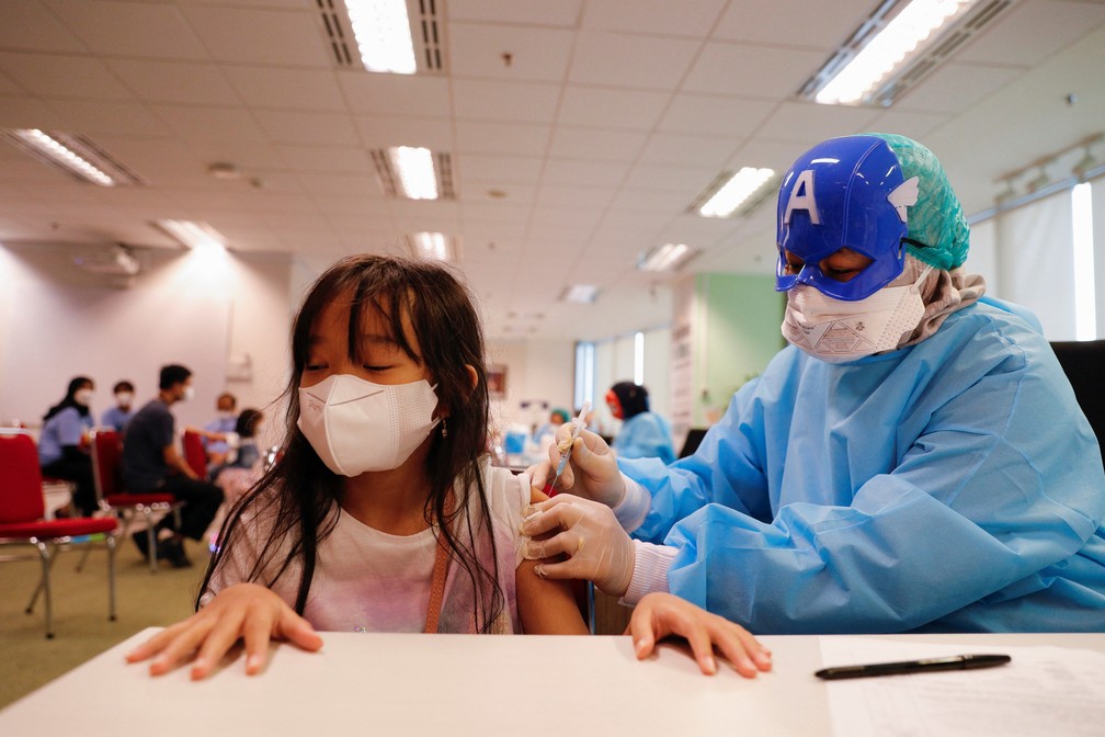Profissional de saúde com máscara do Capitão América vacina menina contra a Covid-19 com a CoronaVac em Jacarta, na Indonésia, em 16 de janeiro de 2022 — Foto: Willy Kurniawan/Reuters