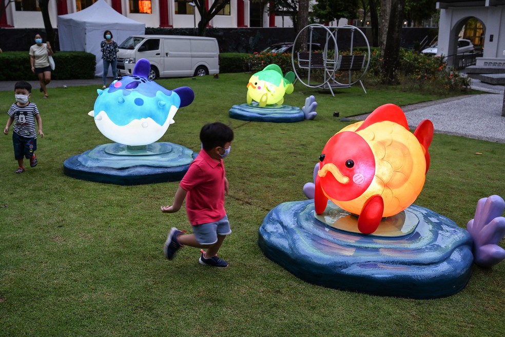 14 de setembro - Adultos assistem crianças brincarem em torno de instalações de lanternas em forma de peixe no Sun Yat Sen Nanyang Memorial Hall, em Singapura  — Foto: Roslan Rahman/AFP