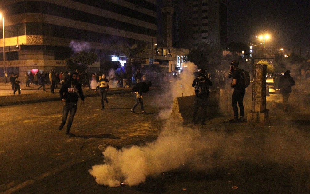  Manifestantes são vistos em meio a fumaça de bombas de gás durante protesto contra lockdown em Tripoli, no Líbano, na noite de quarta-feira (27) — Foto: Reuters/Omar Ibrahim 