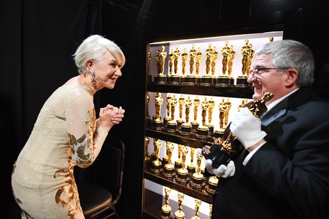 Helen Mirren admira as desejadas estatuetas do Oscar no backstage