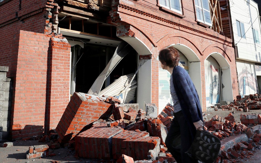 Mulher observa um prÃ©dio destruÃ­do por terremoto em Abira, na ilha de Hokkaido, no JapÃ£o, na manhÃ£ de quinta-feira (6) (Foto: Kyodo/via Reuters)